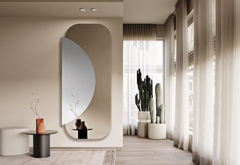 Soggiorno minimalista sui toni del beige con specchio ad arco, tavolo rotondo, cactus e tende trasparenti accanto a una finestra soleggiata.