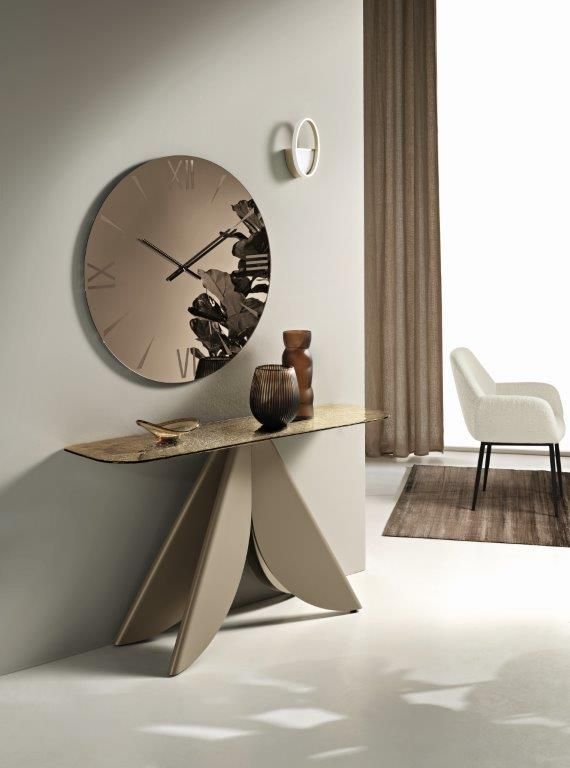 Soggiorno minimalista sui toni del beige con consolle scultorea, specchio rotondo a parete, vaso e sedia bianca vicino alla finestra.