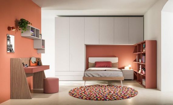 Camera da letto minimalista con armadio a muro bianco, dettagli color corallo e un tappeto rotondo colorato.