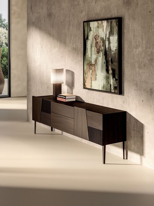 Consolle moderna in una stanza luminosa con lampada, libri e quadro astratto alla parete.