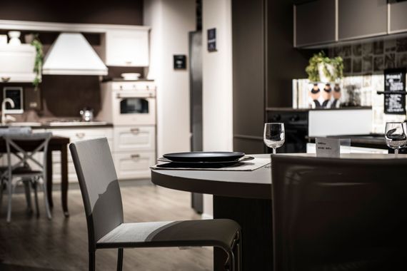 Sala da pranzo moderna del ristorante con tavolo apparecchiato, calici da vino e sedie in penombra.