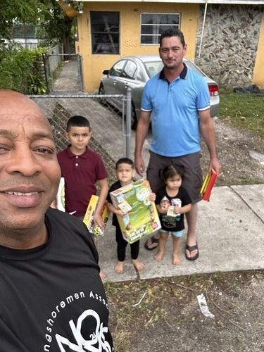 Group of four people posing outdoors in front of a yellow building, two holding snack boxes.