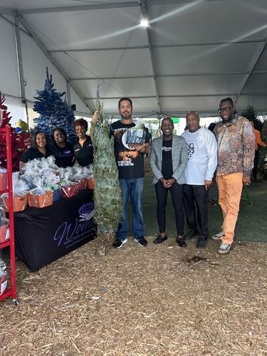 Group of people posing beside a decorated table under a white event tent