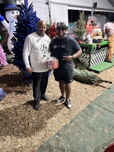Two people standing by Halloween decorations at night, holding a wrapped gift and smiling.
