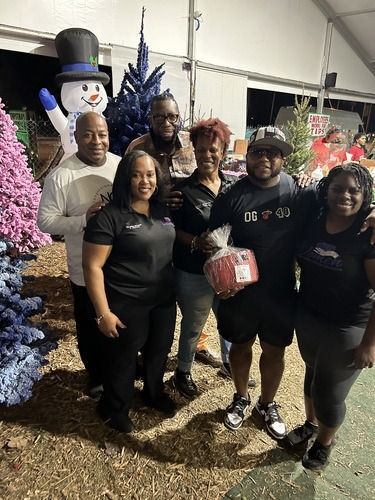 Group posing indoors beside festive holiday decorations and a large snowman display.