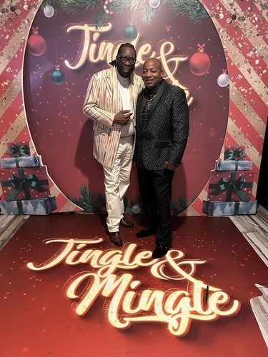 Two people posing on a red carpet at a festive Jingle & Mingle event backdrop