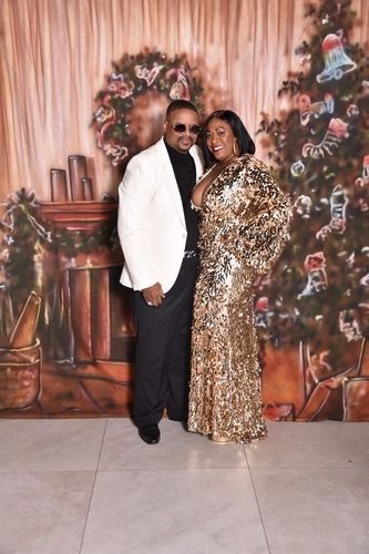 Couple posing in formal attire before a holiday backdrop with a decorated Christmas tree