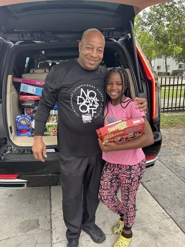 Man and child smiling beside an open SUV trunk with grocery bags and supplies