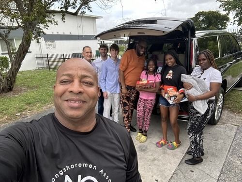 Group posing beside open van on driveway, with one person taking a selfie in front.