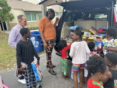 People unloading donations from the back of a van in a neighborhood driveway