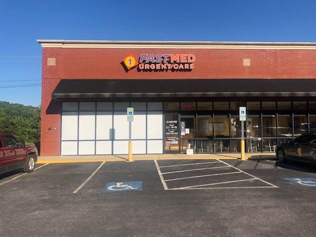 Exterior of a FastMed Urgent Care building with a brick facade, a black awning, and parking spaces.