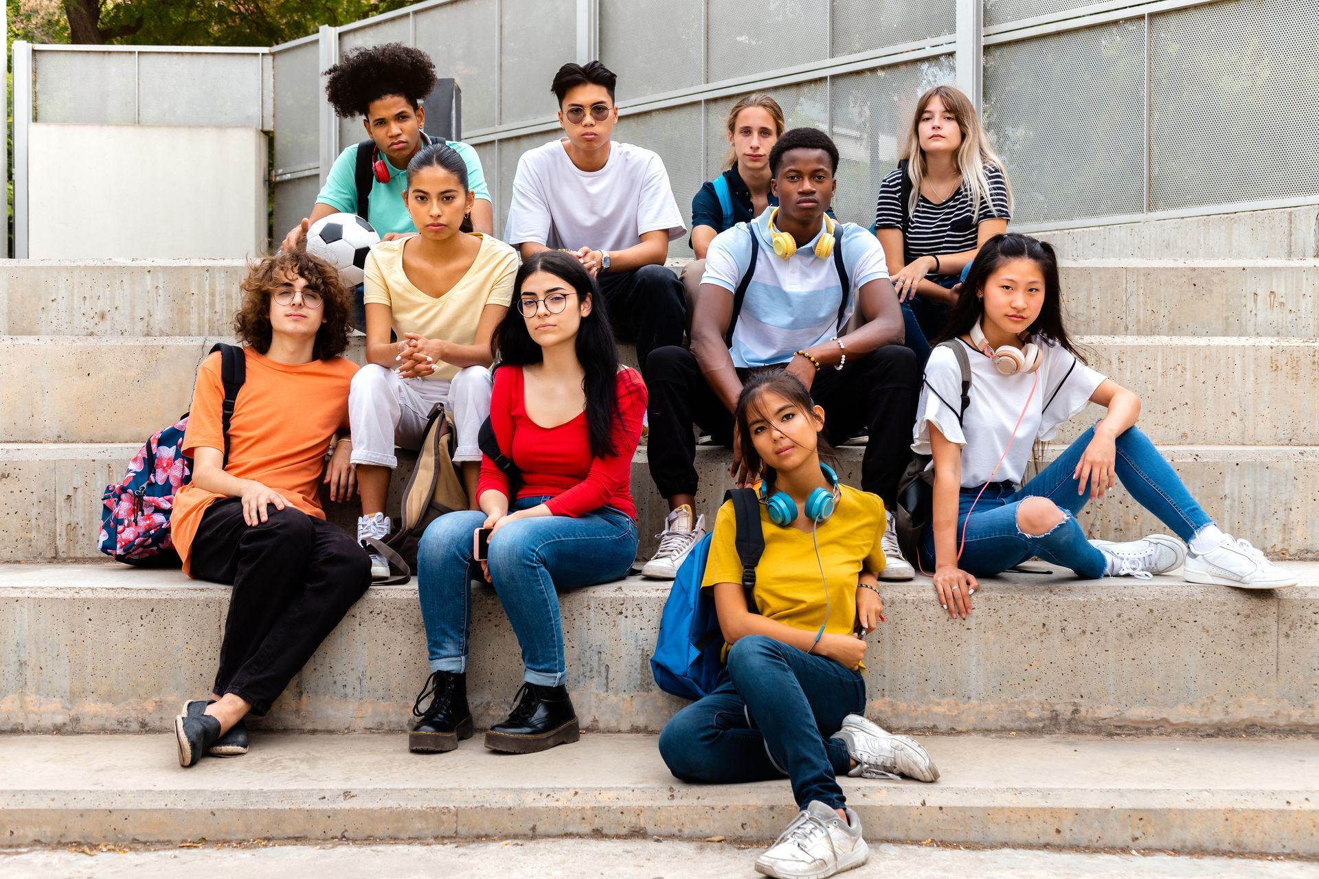 A group of young people are sitting on the steps of a building.