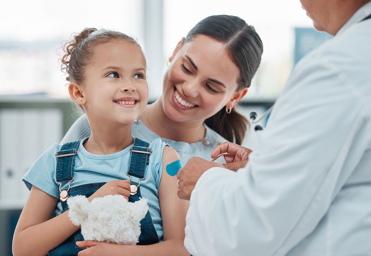 Child smiling as a doctor checks her shoulder in a bright clinic room