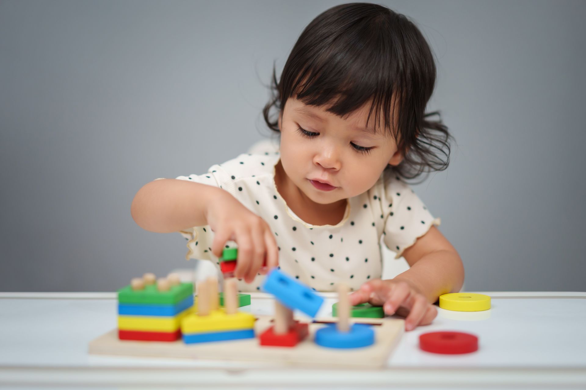 Young child sitting at a table using colorful building blocks.