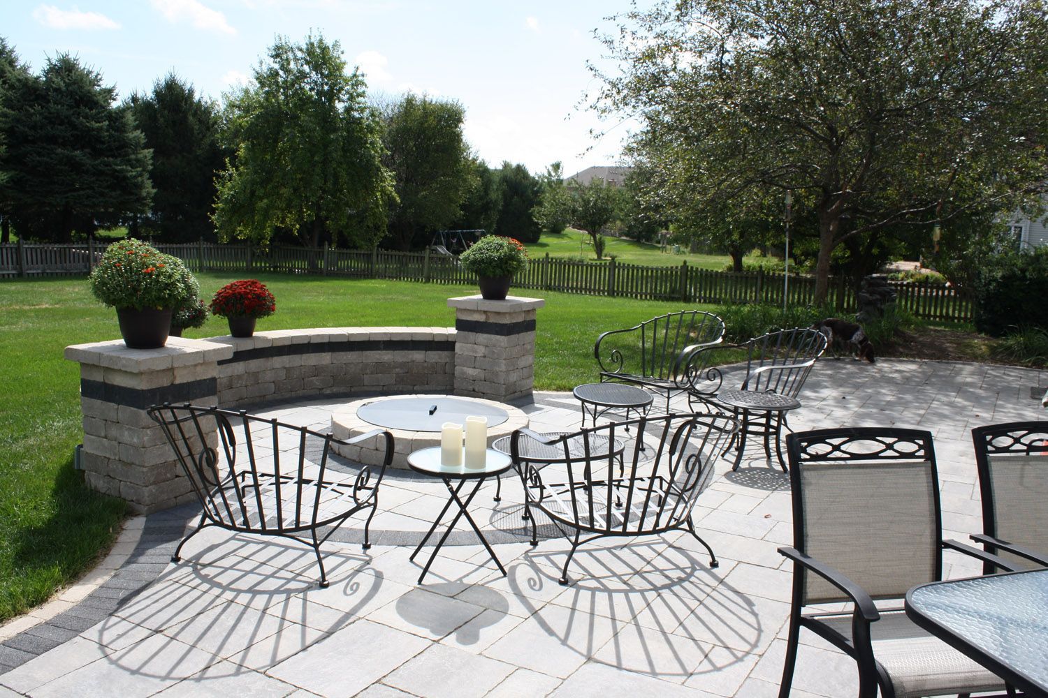 Patio with black metal chairs and table overlooking a green garden and trees
