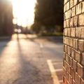 Sunlit brick wall beside an empty street at sunset