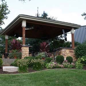 Landscaped garden with a stone pavilion and wooden roof, surrounded by shrubs and flowers