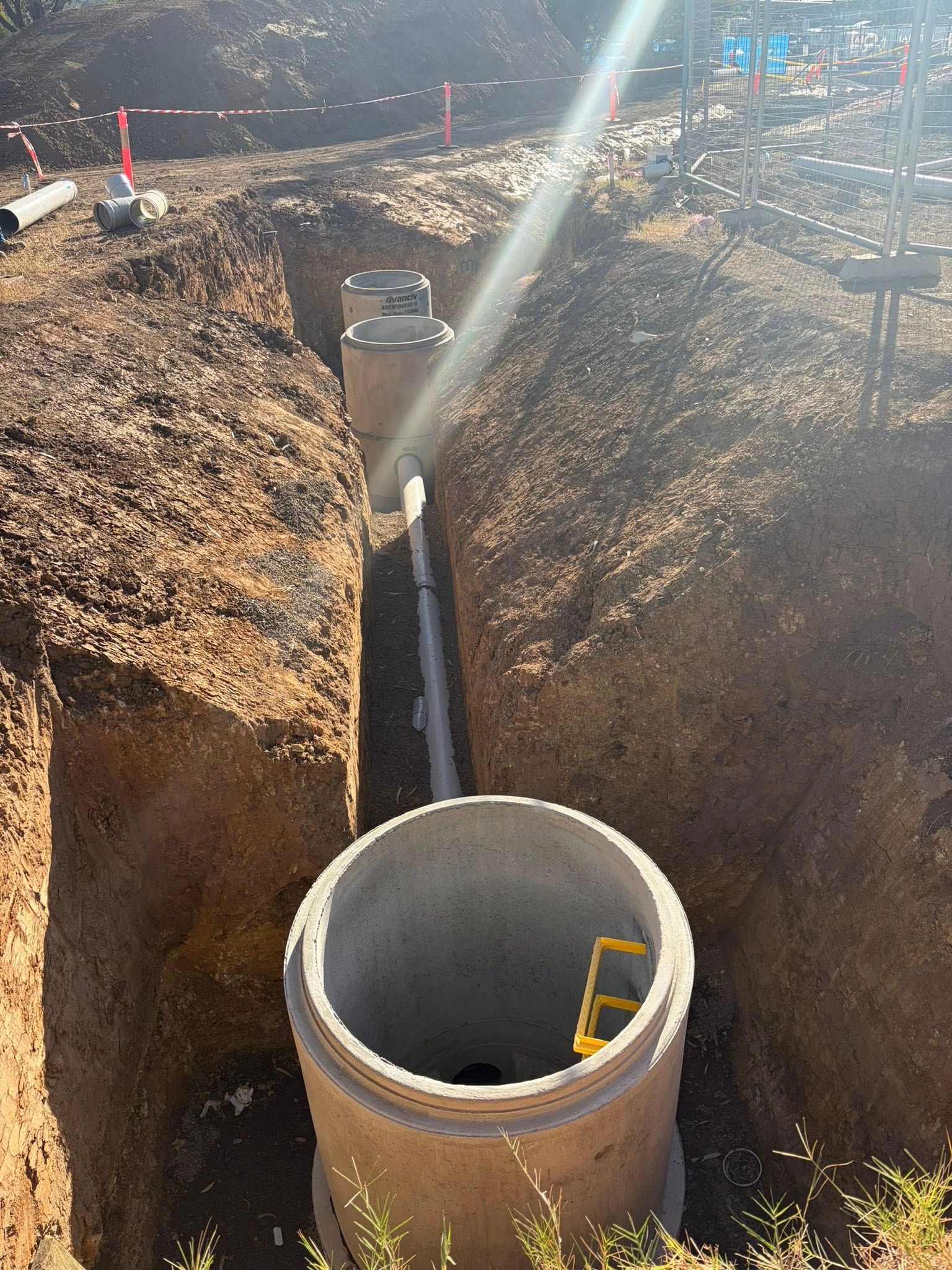 Construction trench with two concrete utility shafts and a ladder, viewed from above. Construction trench with two concrete utility shafts and a ladder, viewed from above.