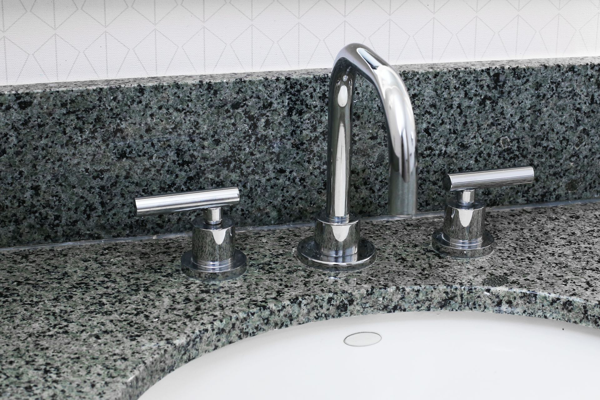 Bathroom sink with chrome faucet and handles on a speckled granite countertop Bathroom sink with chrome faucet and handles on a speckled granite countertop