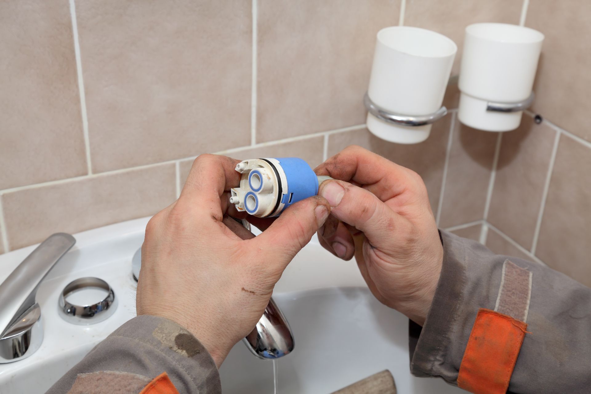 Hands installing a blue shower faucet handle in a tiled bathroom sink area Hands installing a blue shower faucet handle in a tiled bathroom sink area