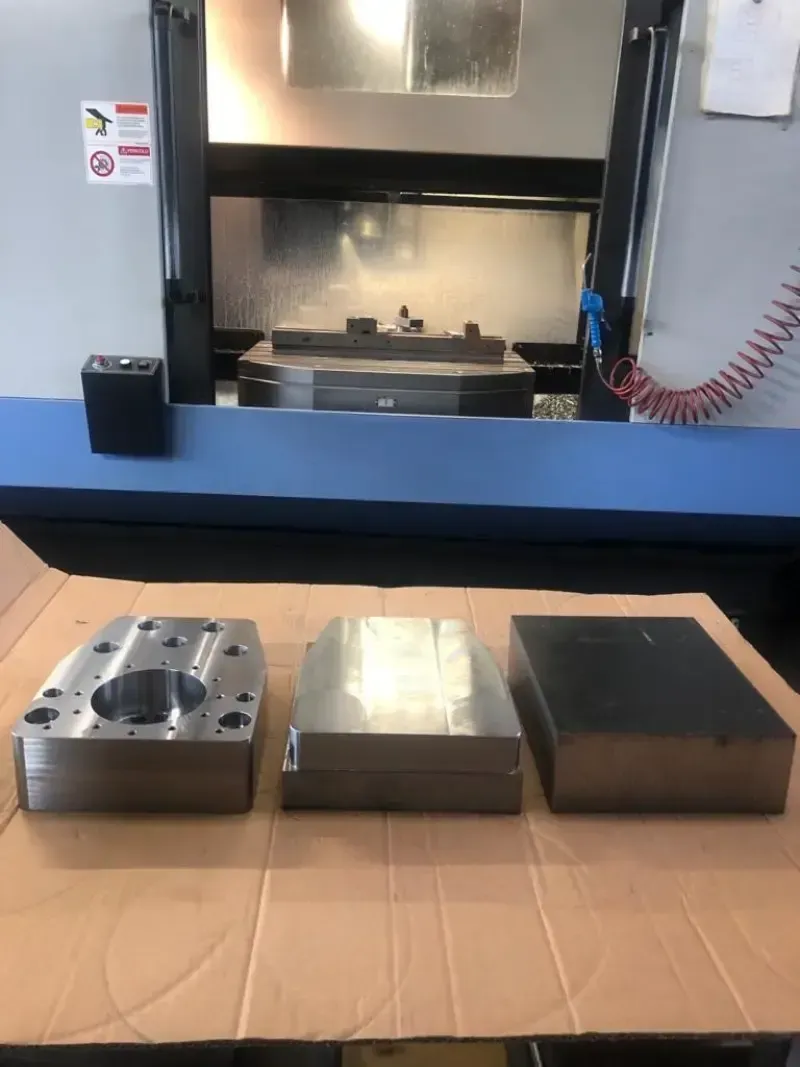 Tre stampi metallici sono posizionati davanti a una pressa per metalli in un'officina.