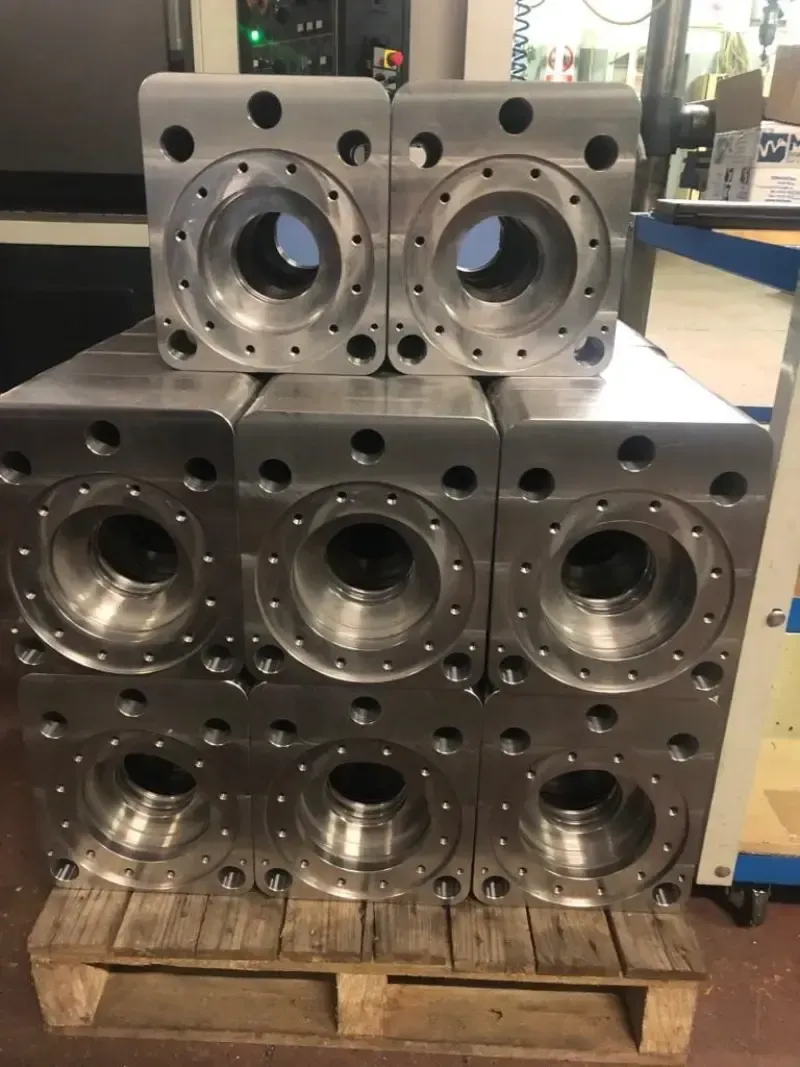 Parti metalliche di macchinari, probabilmente alloggiamenti, impilate su un pallet di legno.