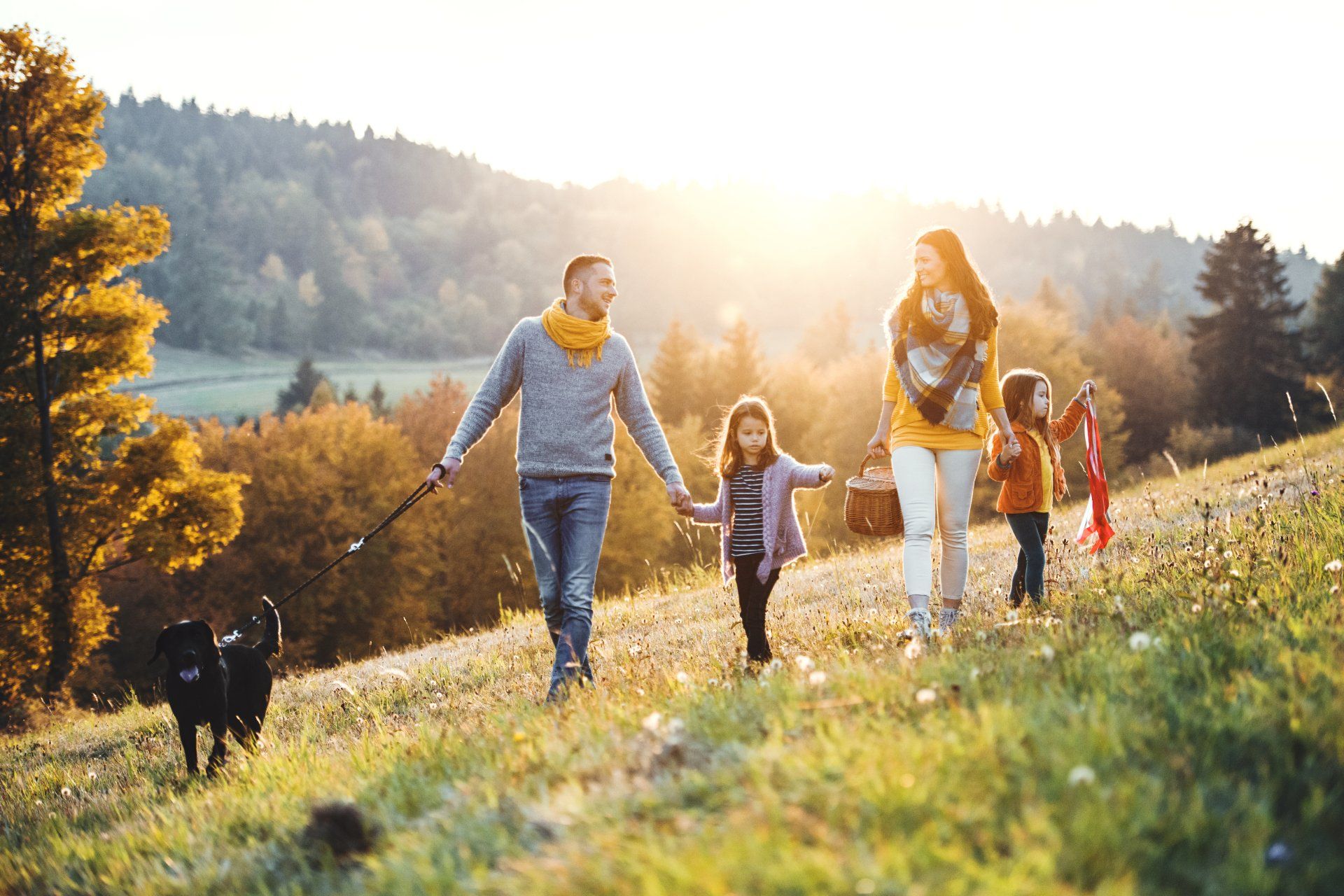 A family is enjoying the outdoors with mother and father holding children's hands.