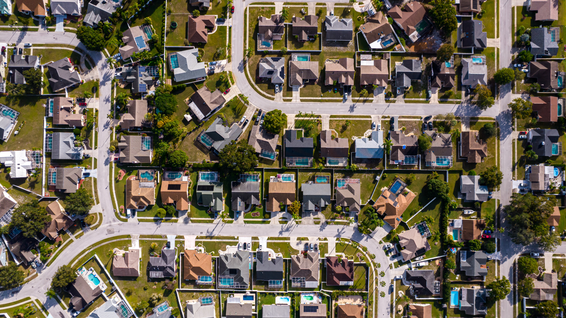 Aerial view of a suburban neighborhood with rows of houses, streets, and trees.