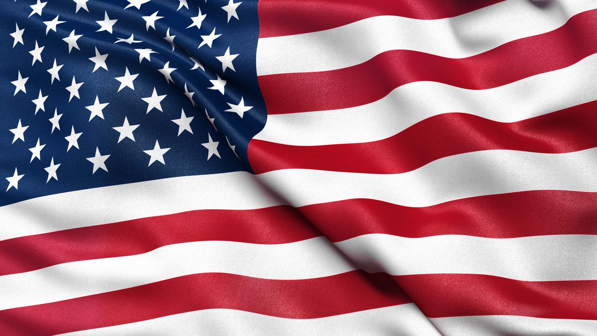 U.S. flag waving, with stars and red-and-white stripes in the wind