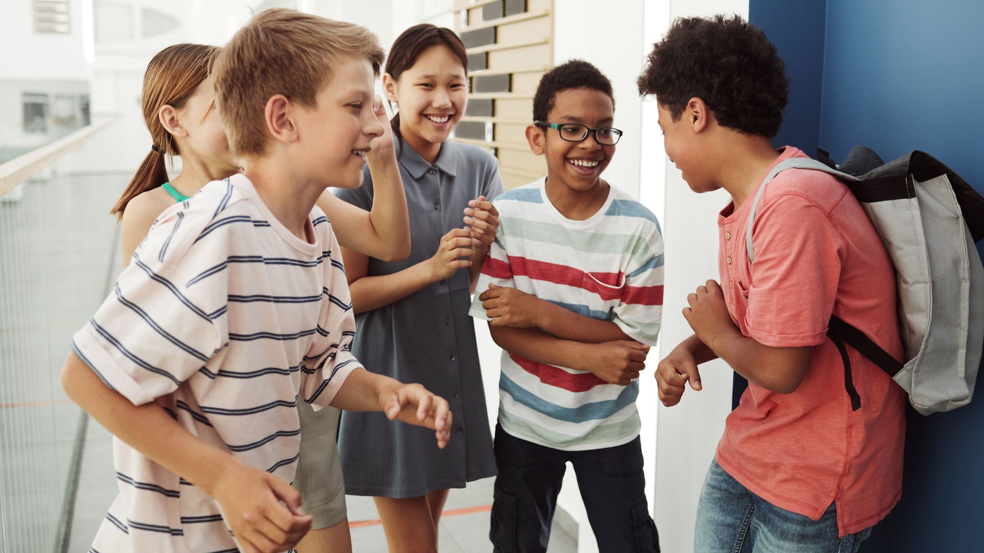 Group of children laughing and chatting together indoors, standing in a bright room.