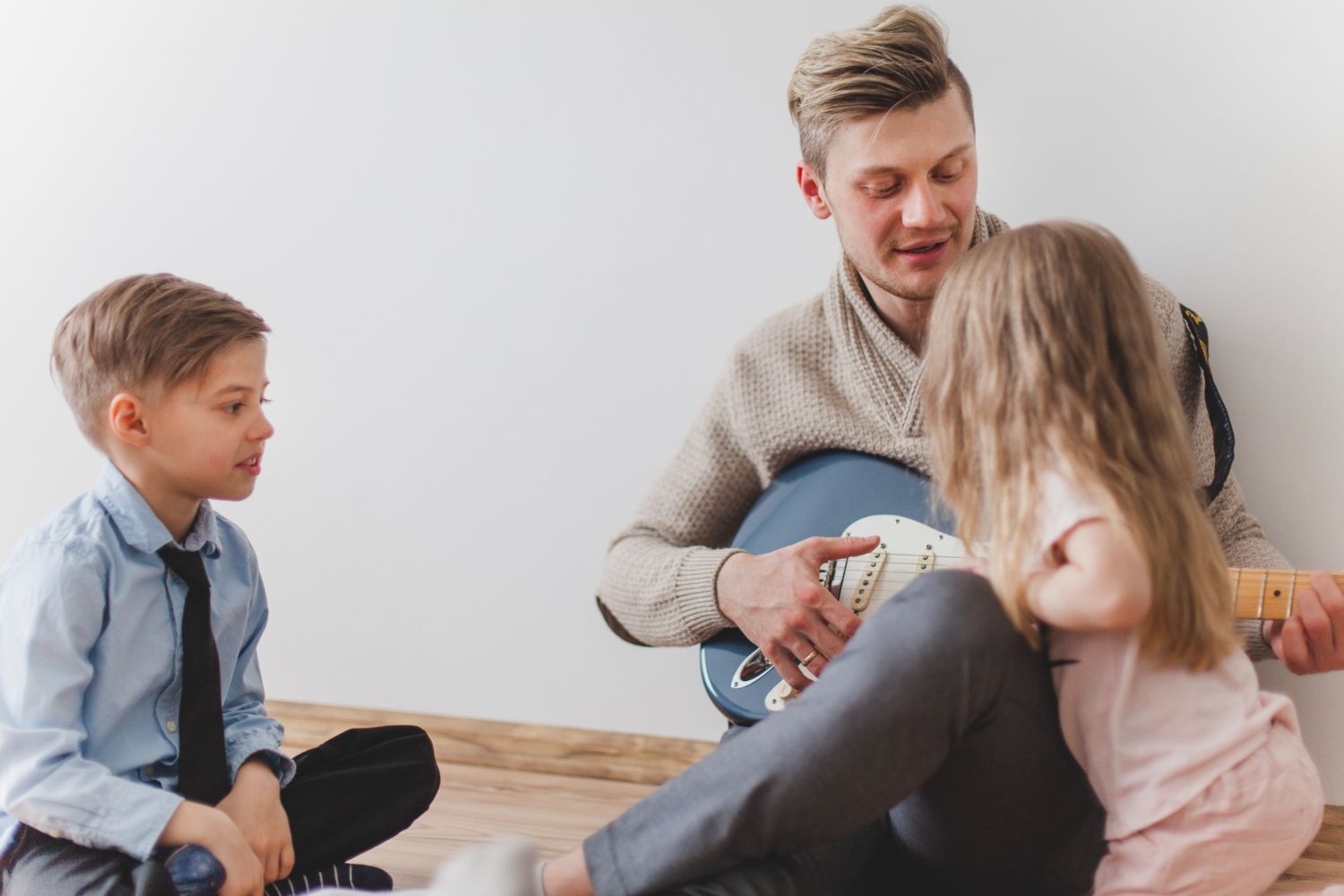 Adult reading to two children on the floor in a bright room