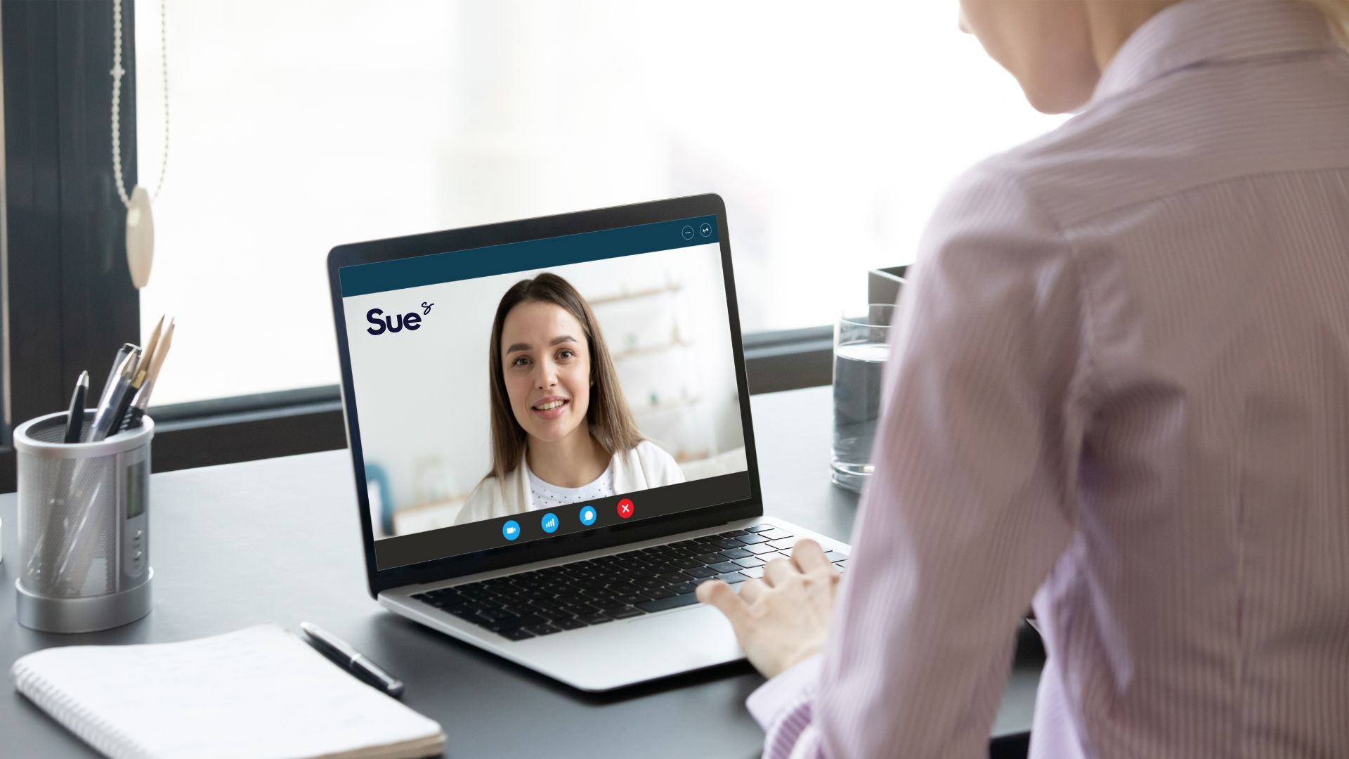 Person on a laptop video call with a smiling woman in a home office