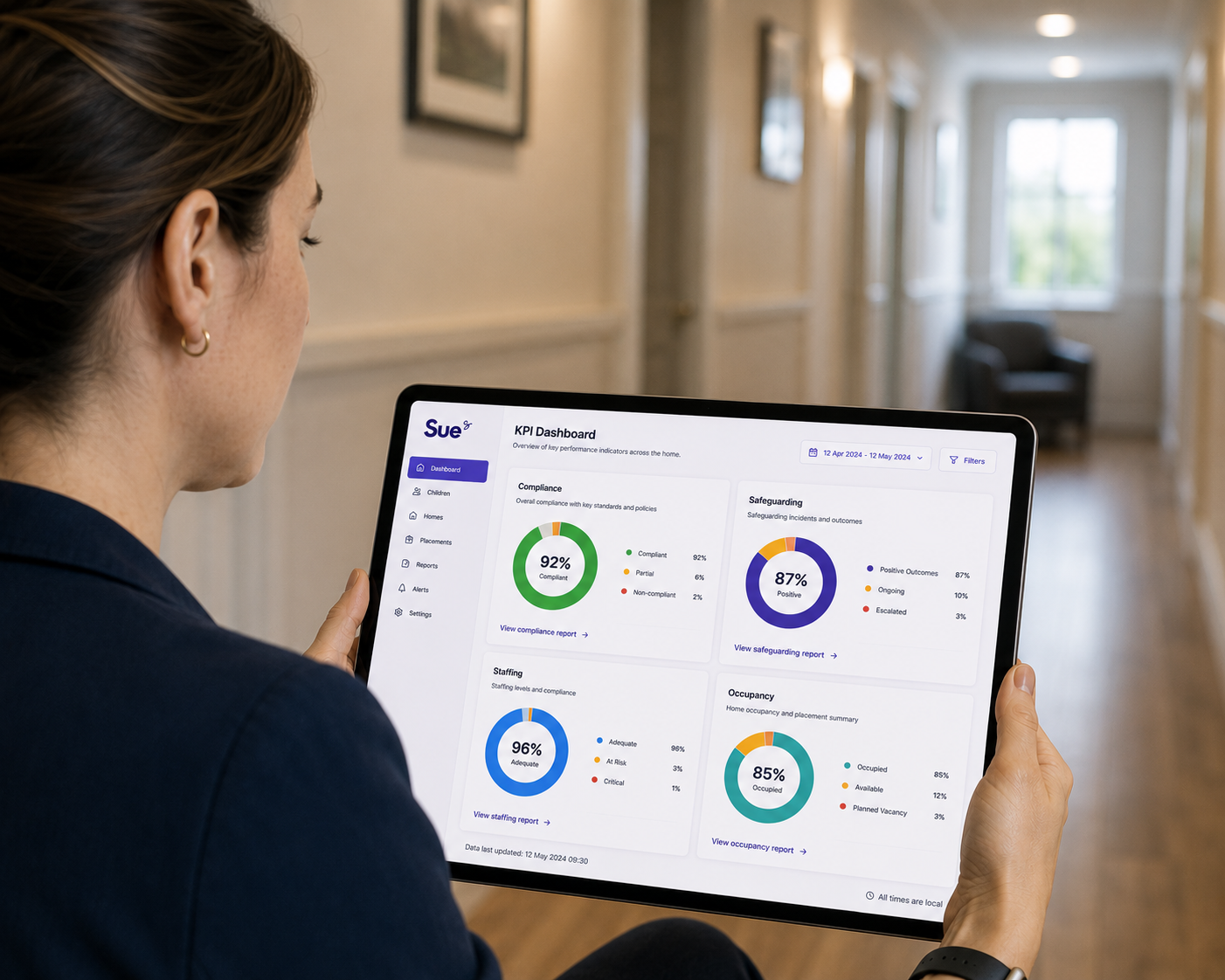 Person viewing a tablet dashboard with four colorful analytics charts in a hallway
