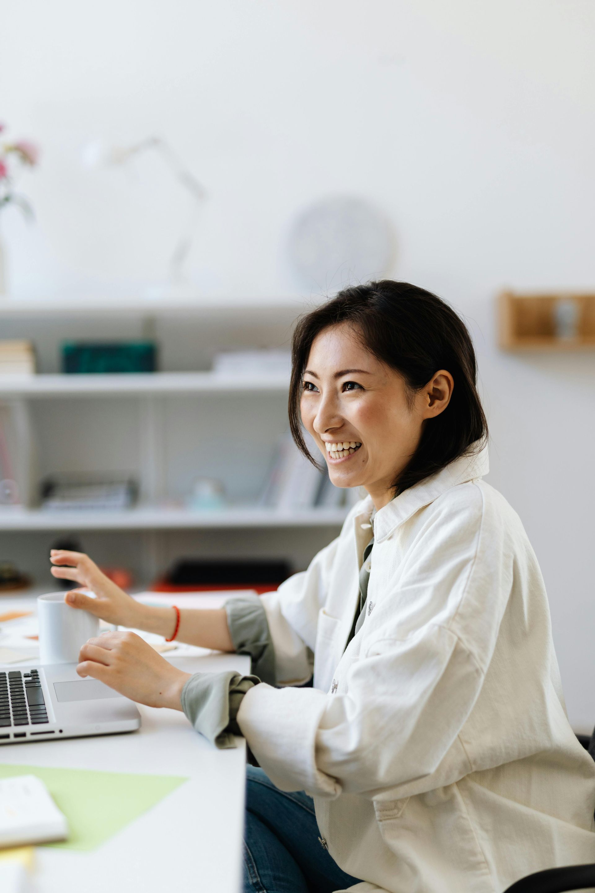 Woman smiling and talking at a desk with a laptop in a bright office