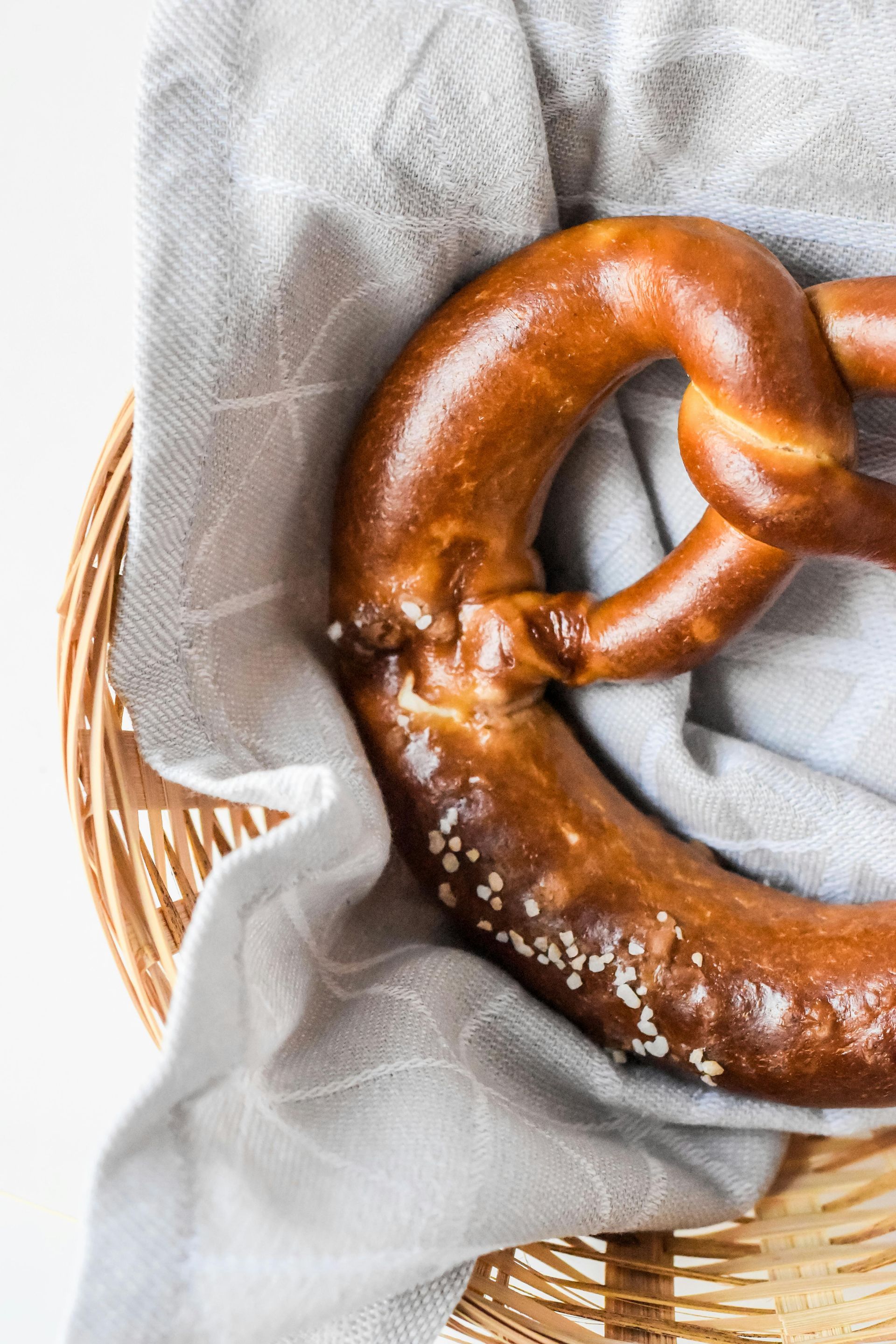 Pretzel in a wicker basket on a grey cloth.