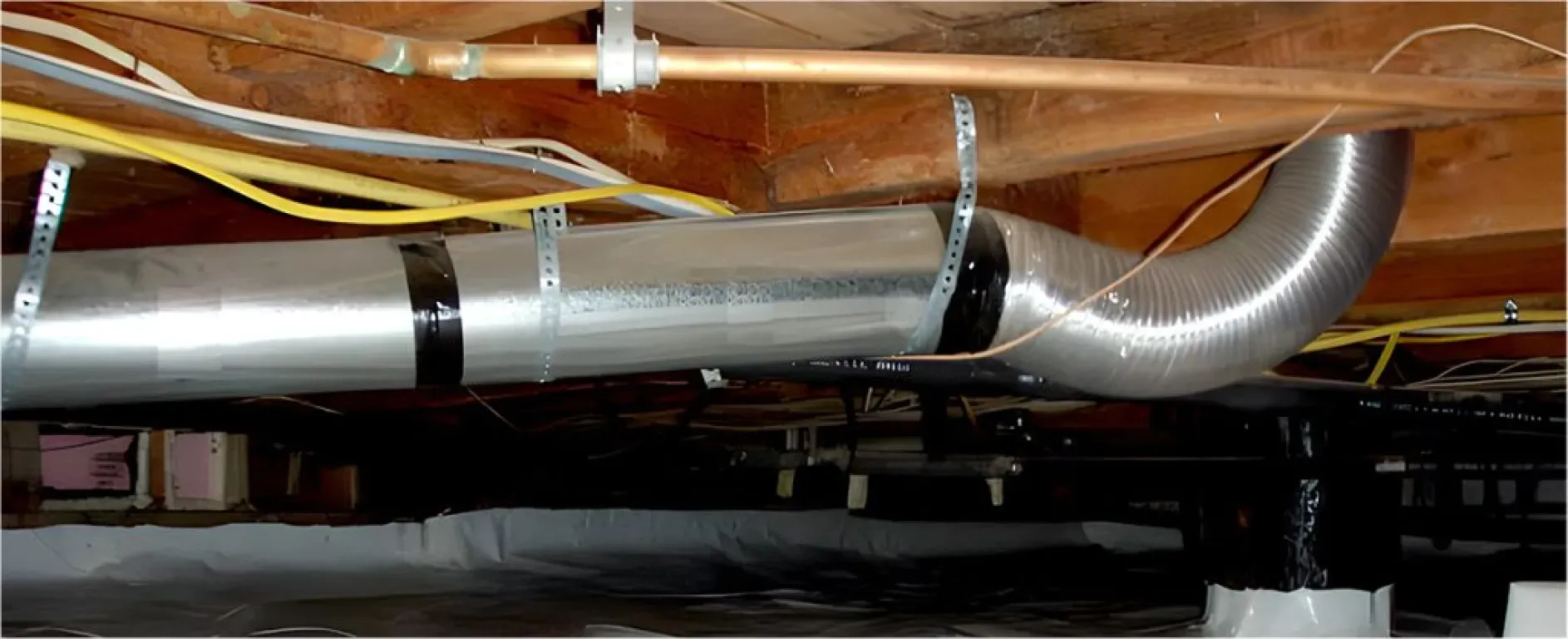 A metal pipe is hanging from the ceiling of a basement.