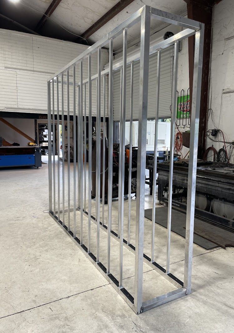 Metal frame with vertical bars, possibly a cage or display structure, in a workshop.