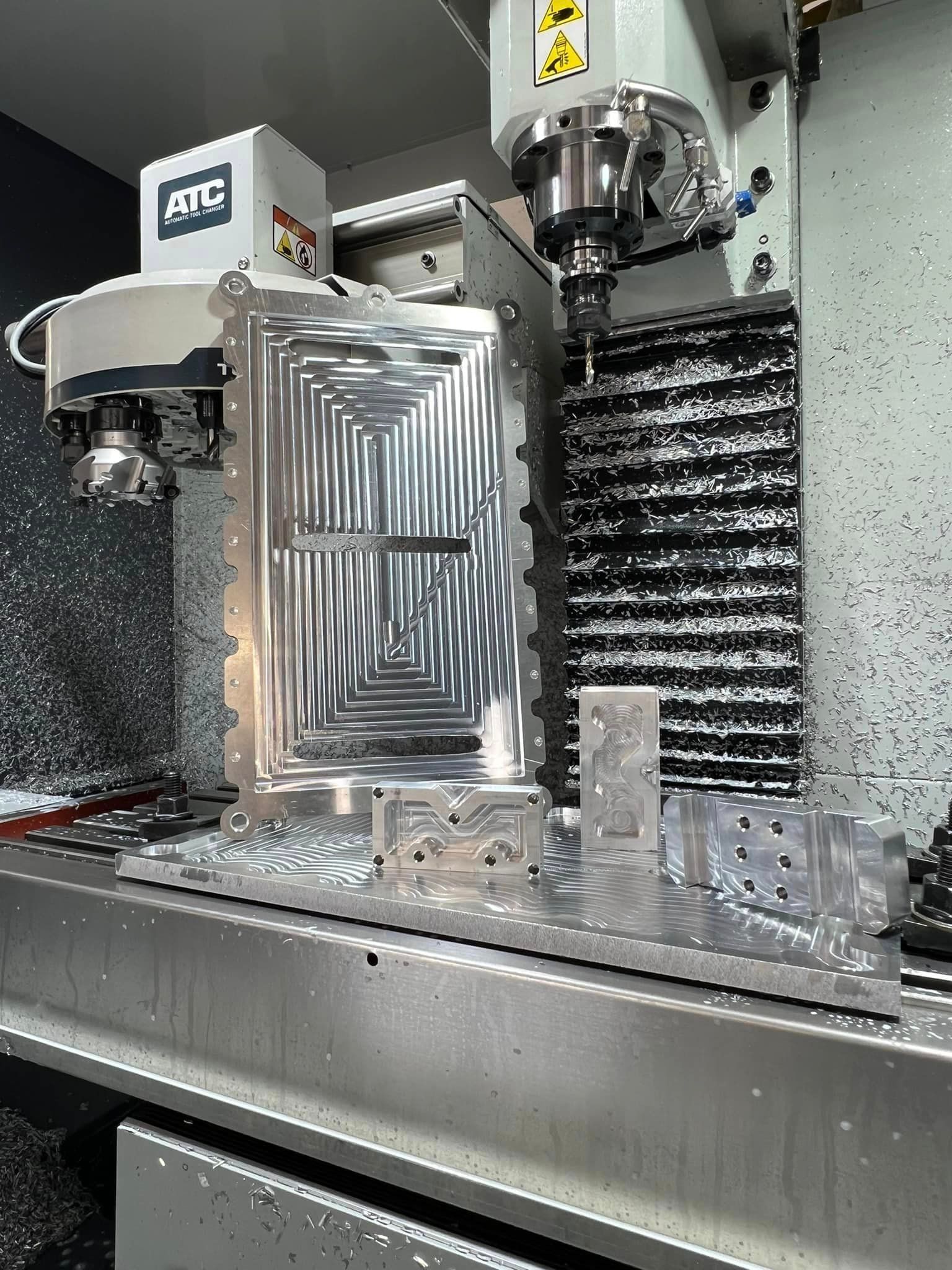 CNC milling machine machining a complex aluminum part with a spiral pattern.