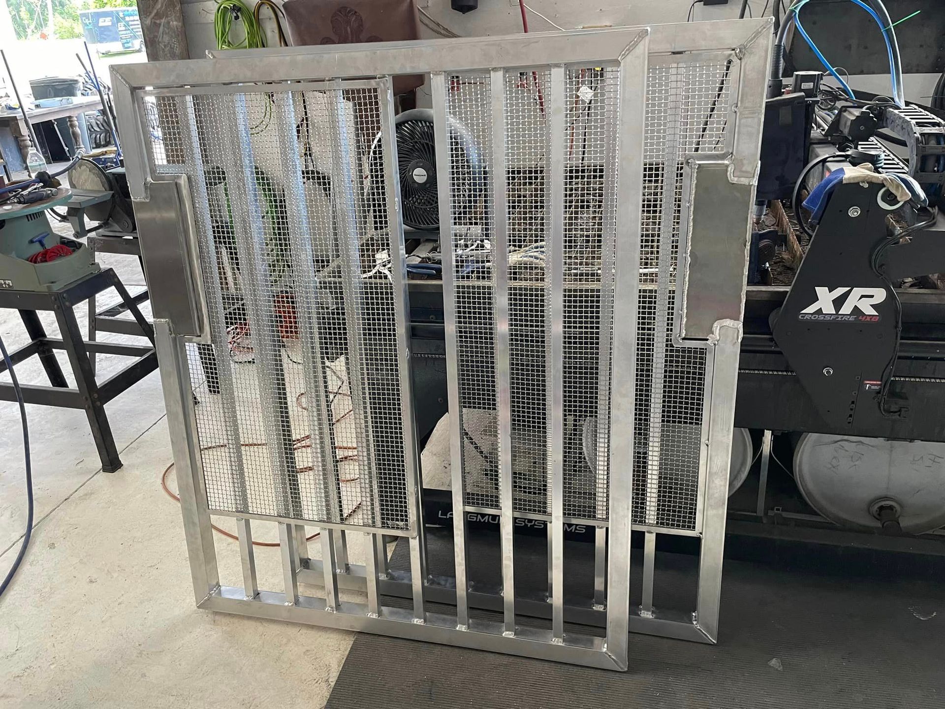 Aluminum metal cage with vertical bars, possibly for a vehicle or pet. Shop background.