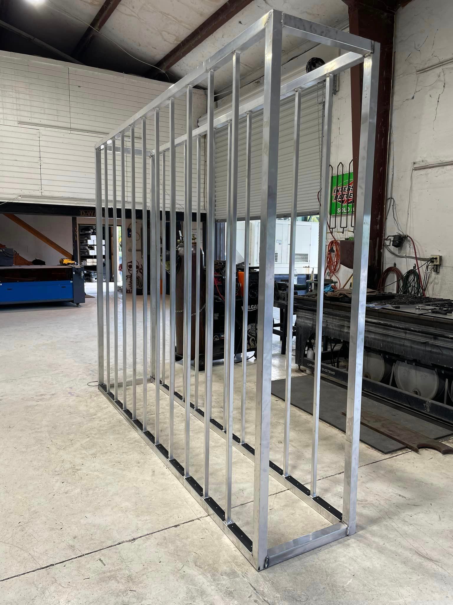 Metal frame cage, constructed with vertical bars inside a rectangular structure, in an industrial setting.