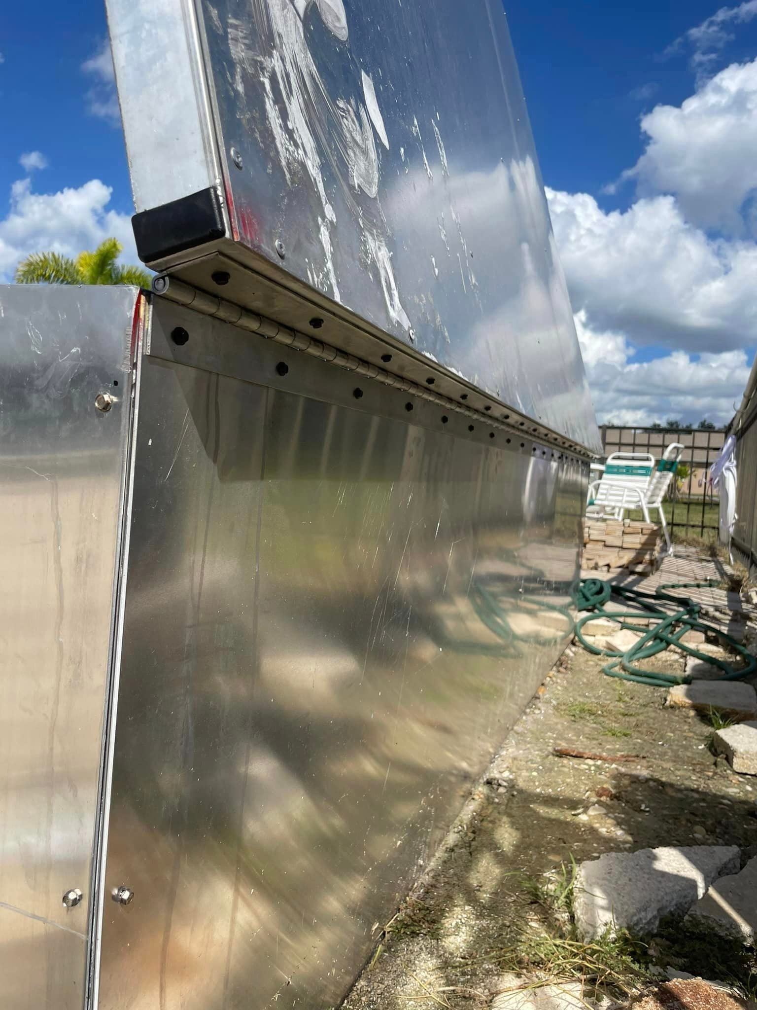A shiny, stainless steel wall with a black trim, outdoors in a sunny setting.