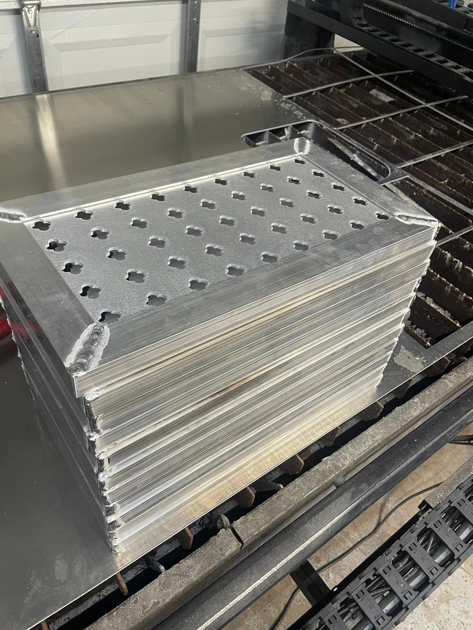 Stack of cut metal pieces with patterned holes, likely for industrial use.
