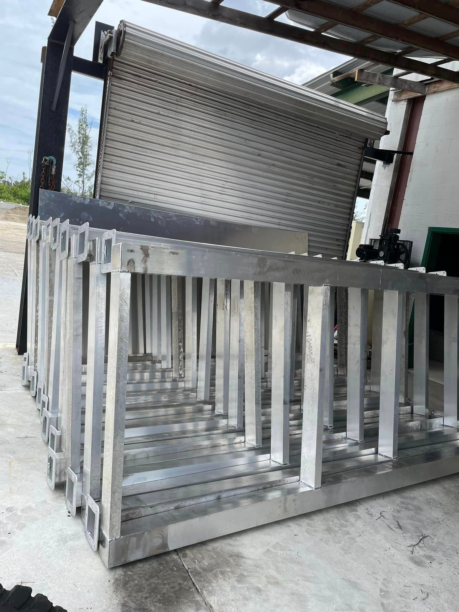Aluminum frames stacked in front of a closed garage door in an outdoor setting.