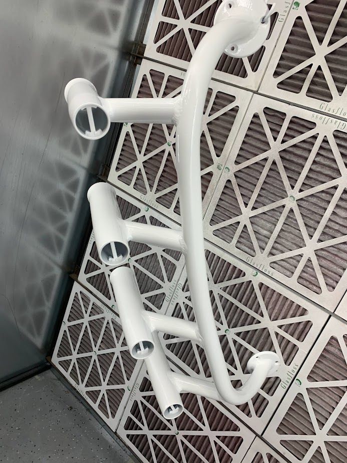 White metal tubes arranged in a complex shape, possibly a frame or structure, on a grid.