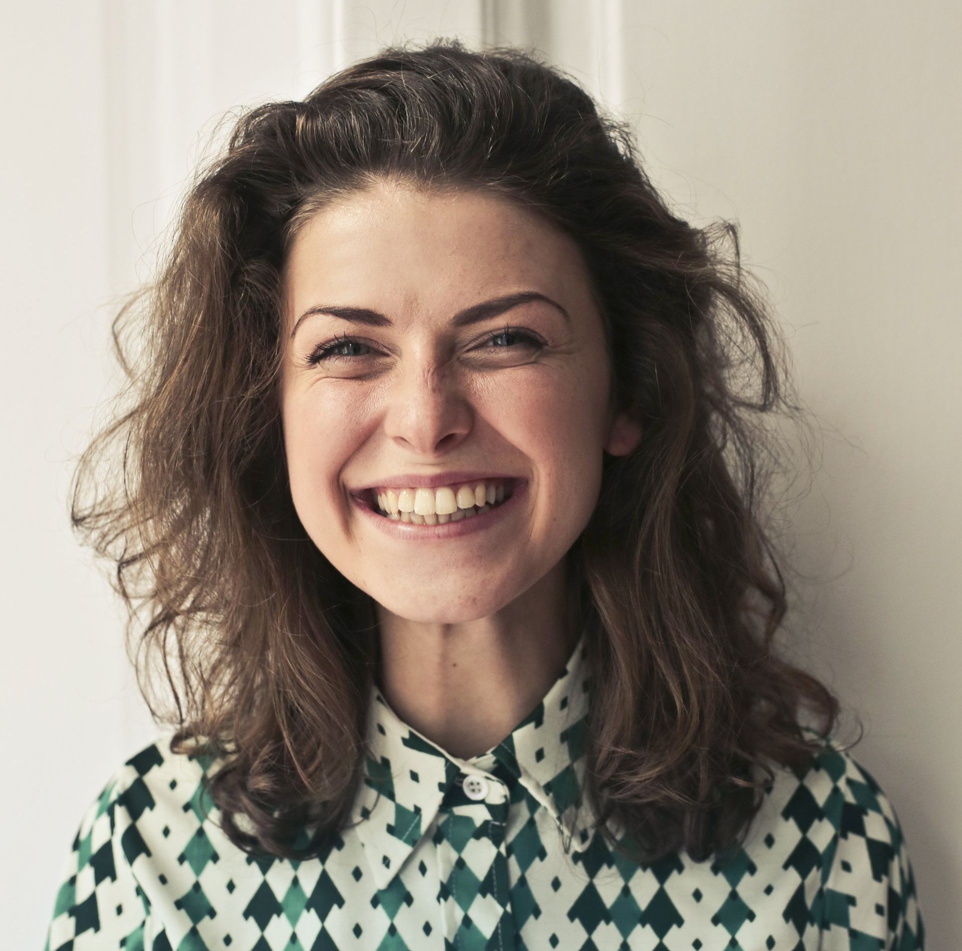 A woman wearing a green and white checkered shirt is smiling
