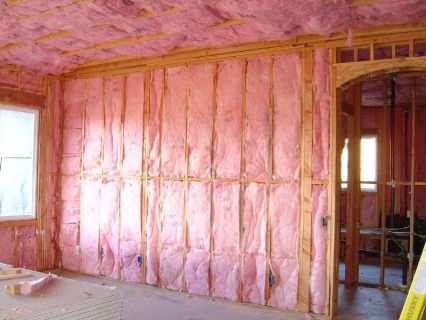 Interior room under construction with pink fiberglass insulation in the walls and ceiling.