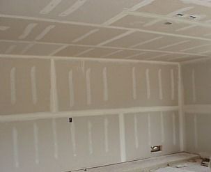 Unfinished drywall room with taped seams and a small wall opening