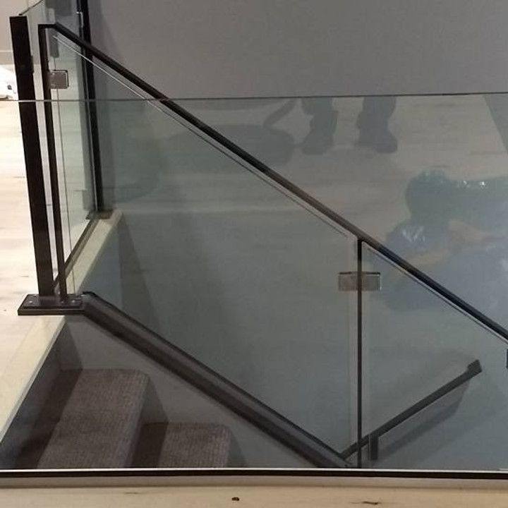 Glass and black metal railing beside a staircase. Gray wall in background.