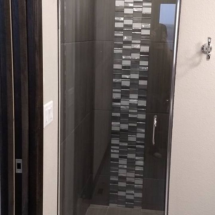 Shower with glass door, dark gray tile with a vertical band of mosaic tile. Silver hardware.