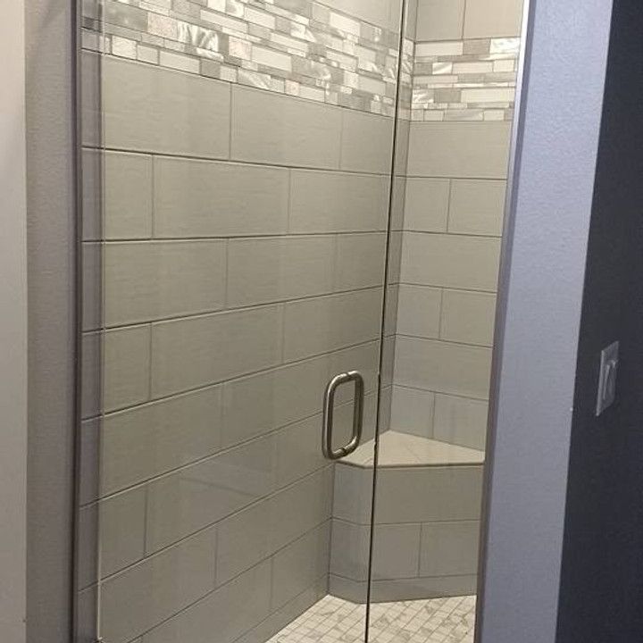 Glass shower with gray tile walls and bench seat.
